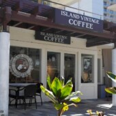 Island Vintage Coffee storefront at Whalers Village in Kaanapali, with outdoor seating and ti plants in front.