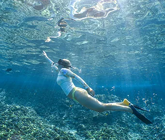Woman snorkeling over a vibrant Maui coral reef, capturing respectful exploration of Kanaloa’s ocean realm
