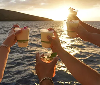 Guests aboard the Pride of Maui ʻElua raising drinks to celebrate a stunning sunset over Maui’s ocean.