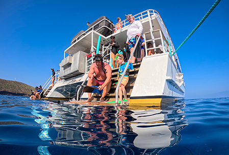 Snorkelers entering the water from a Pride of Maui boat on a calm Molokini morning