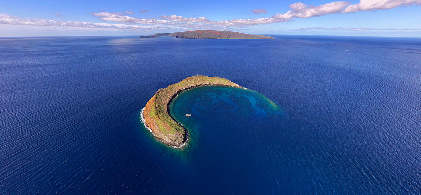 Aerial view of Molokini Crater off Maui with snorkel boats moored inside the crescent